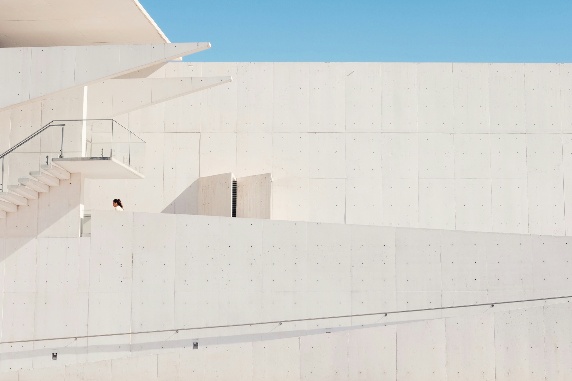 White concrete building with terraces against a blue sky